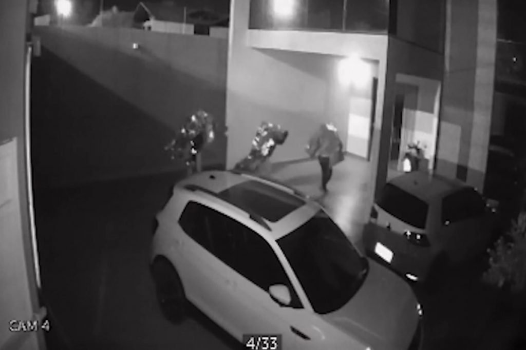 Três homens cobertos com pedaço de material brilhante vasculha residência