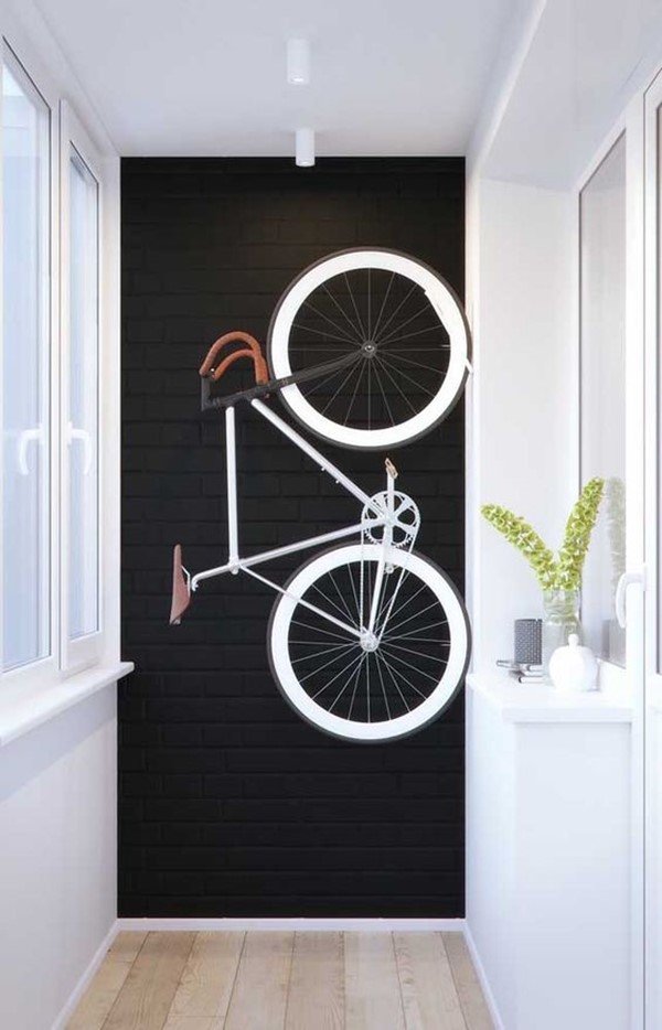 Imagem colorida de uma parede preta e uma bicicleta pendurada nela