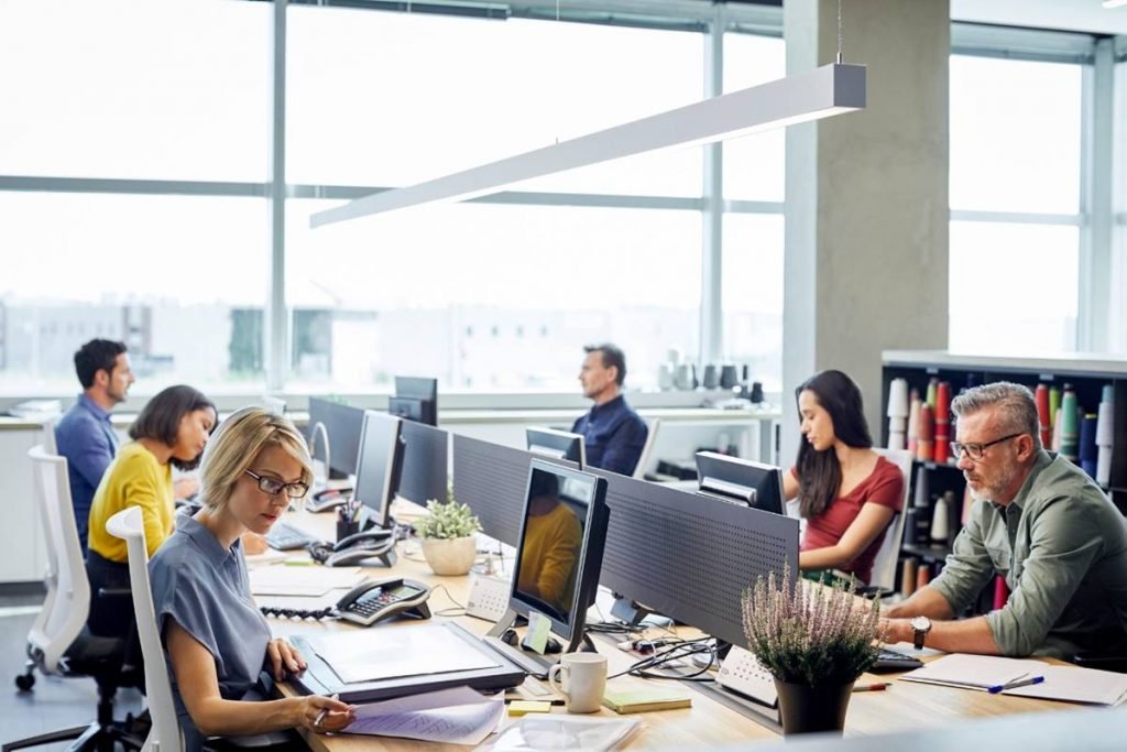 foto colorida de um escritório com vários funcionários trabalhando