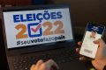 mão segura celular aberto no aplicativo do e-titulo desfocado e ao fundo a logo eleições 2022