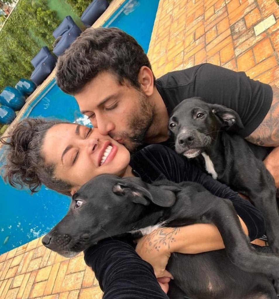 foto colorida de um homem e uma mulher segurando cachorros