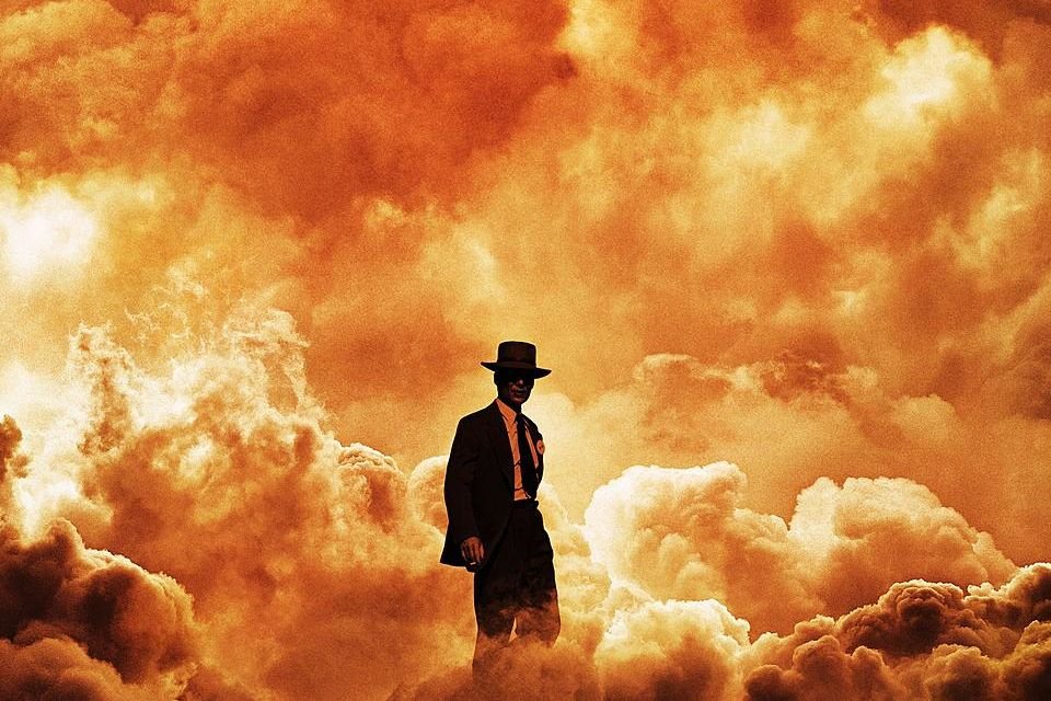 Cena de Oppenheimer, filme do diretor Christopher Nolan. Na imagem, um homem vestindo termo e chapéu caminha no meio de uma explosão - Metrópoles