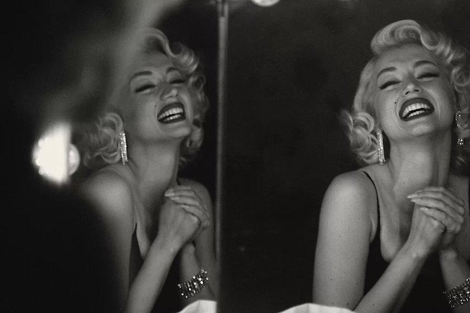 Cena do filme Blonde, cine biografia da atriz Marylin Monroe. Na cena, a personagem aparece diante de um espelho, rindo - Metrópoles