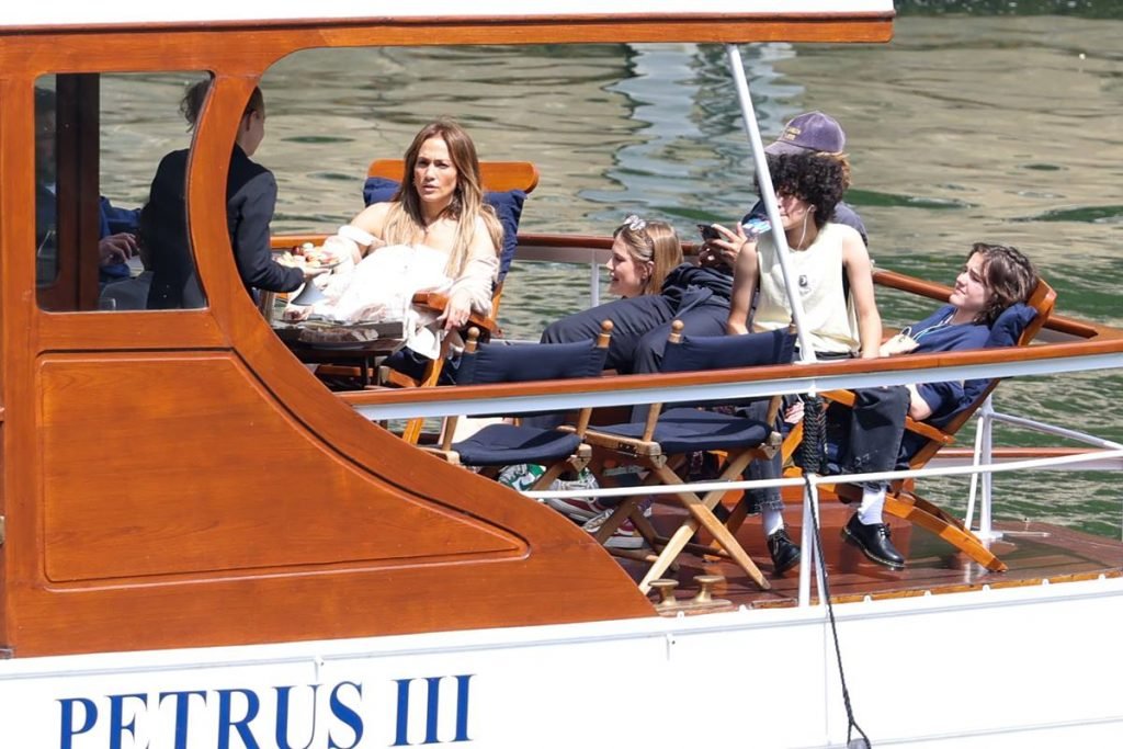 Foto colorida. Mulher, homem e adolescentes em um barco