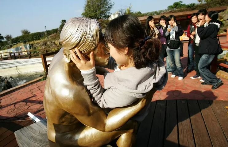 foto colorida de mulher abraçando escultura