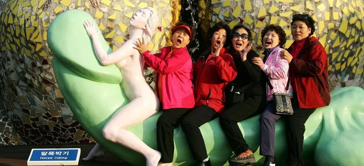 foto colorida de mulheres em cima de um pênis gigante