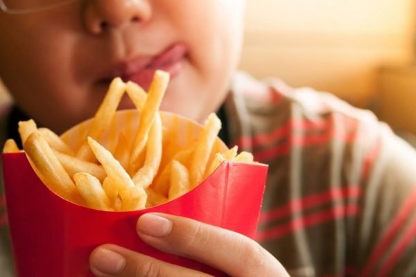 Menino obeso comendo batata frita - Metrópoles