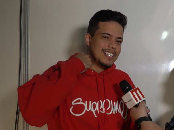 felipe amorim de moletom vermelho falando no microfone do metrópoles