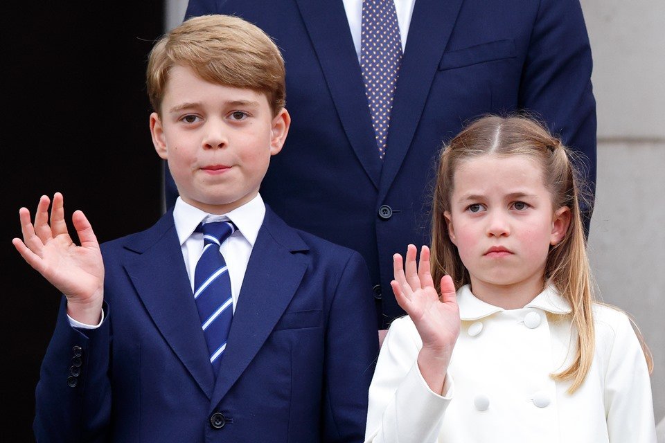 Foto colorida. Menino e menina lado a lado acenando