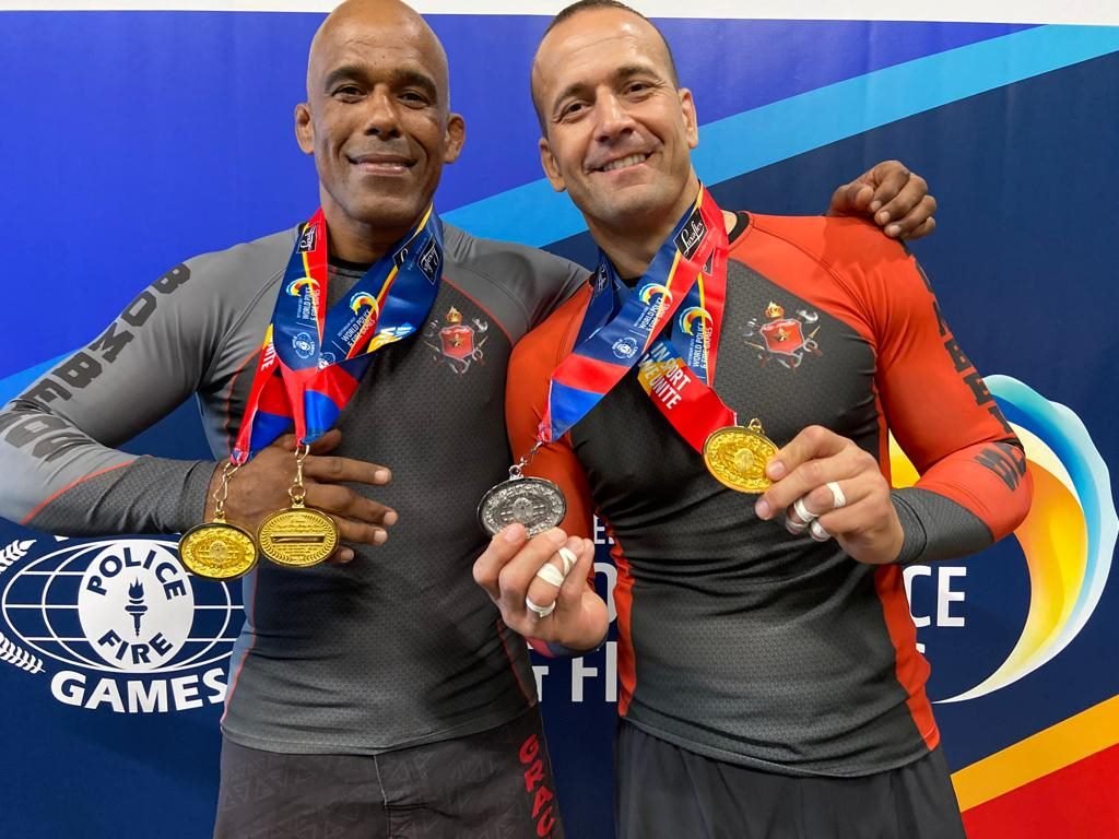 Homens em roupas térmicas se abraçam e seguram medalhas
