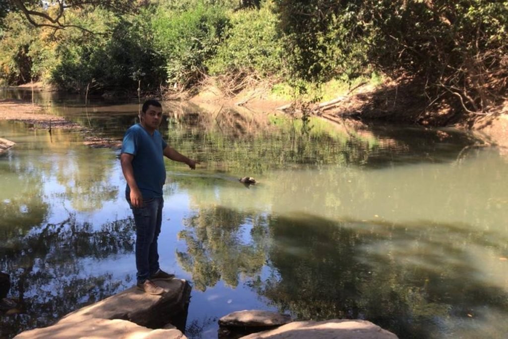 Leonardo Oliveira da Silva mostra água em cor esverdeada no Rio dos Bois, região de Campos Verdes, Goiás