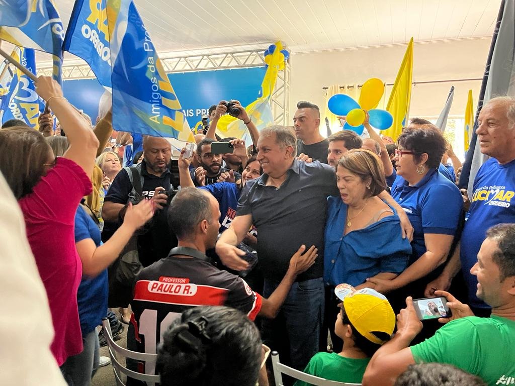foto colorida homens e mulheres com roupas azuis e amarelas abraçados