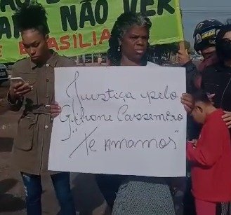 Mulher segura cartaz pedindo justiça