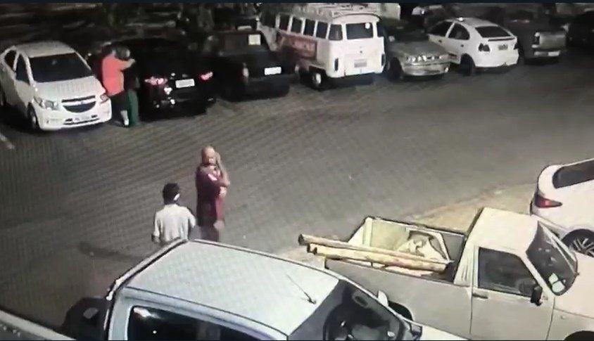 Homem de camisa roxa anda pelo estacionamento