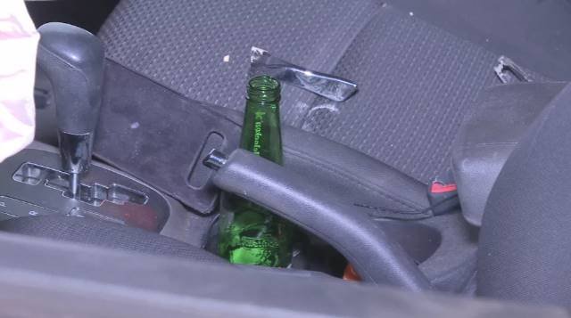 foto colorida de garrafa de cerveja dentro de carro