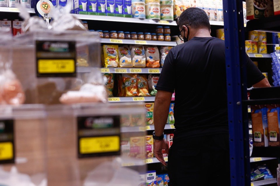 Homem de costas olhando para prateleira de supermercado