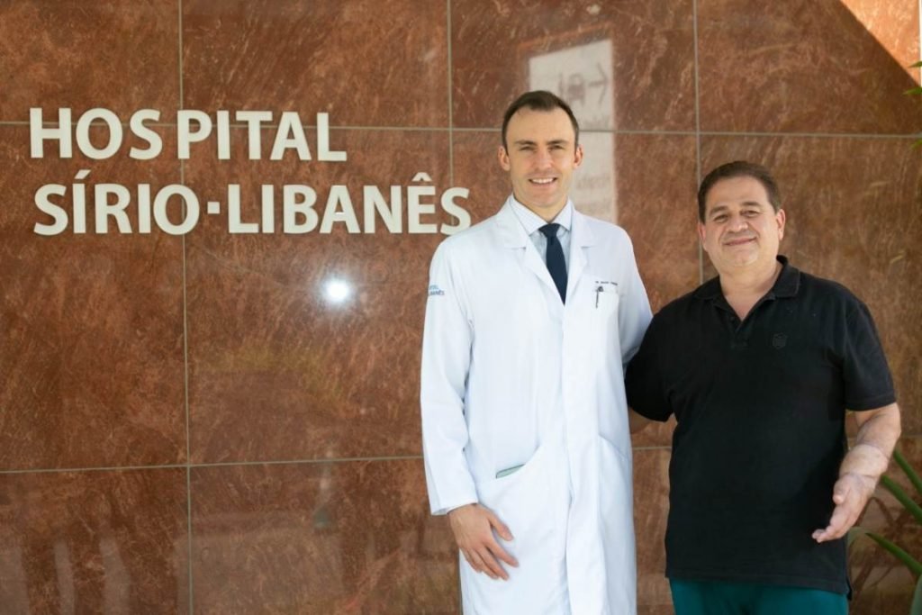 fotografia colorida de médico e paciente em frente à fachada do hospital Sírio Libanês, em Brasília