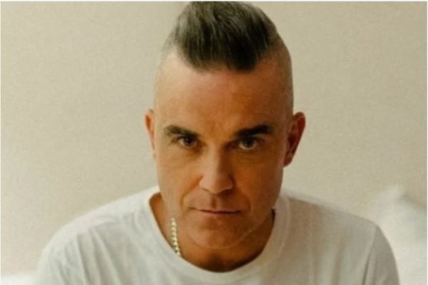 Foto colorida do cantor Robbie Williams - Metrópoles