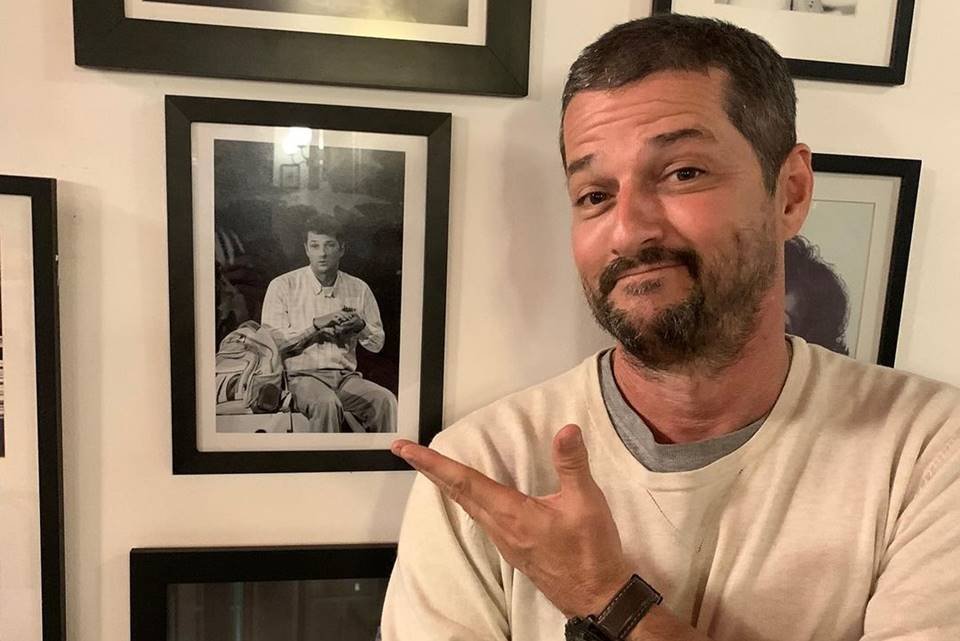 Foto colorida de Marcelo Serrado apontando para um quadro - Metrópoles