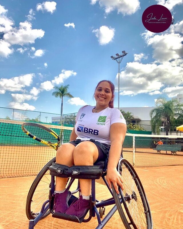 Jade de tênis roxo, blusa branca e sorrindo para foto