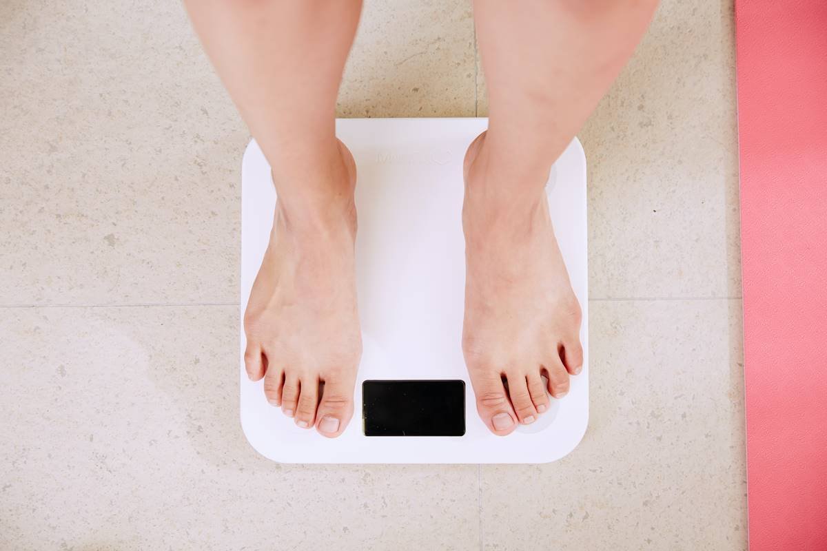 Foto colorida de balança. Pessoa tentando perder peso