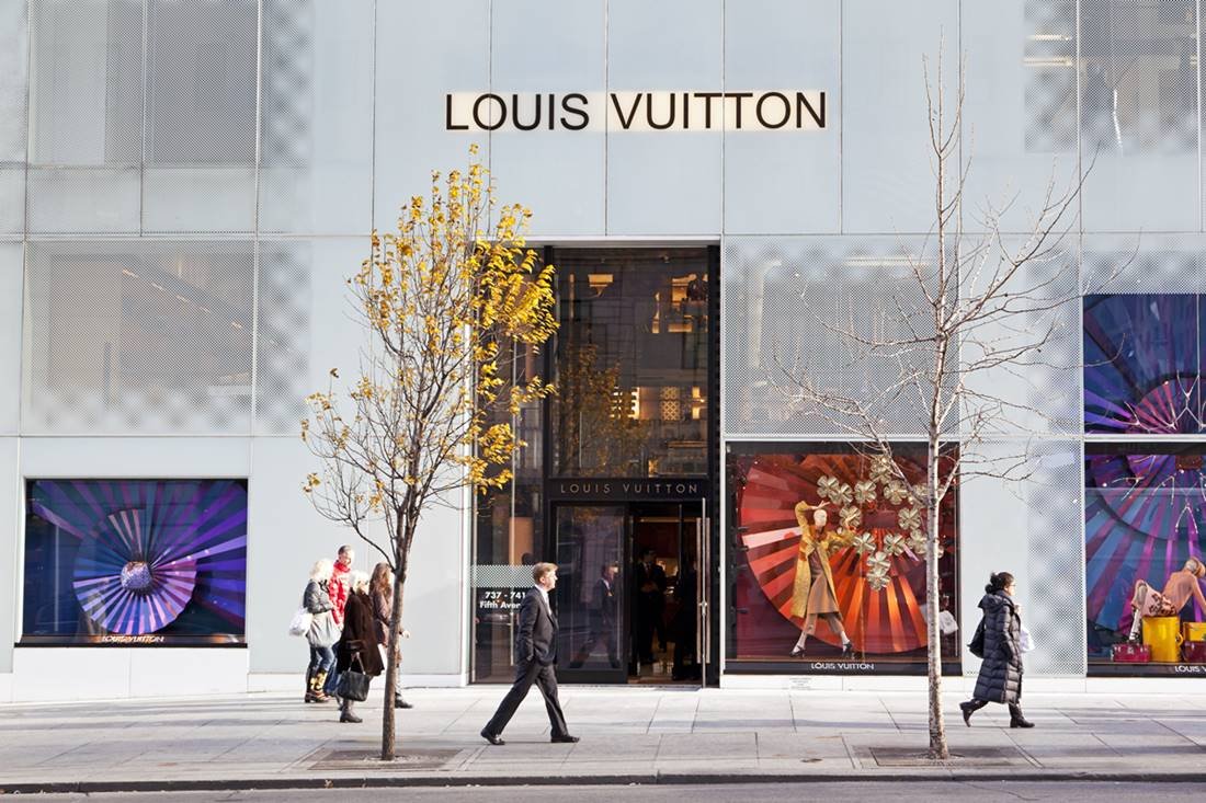 Fachada da loja da marca de luxo francesa Louis Vuitton. É possível ver, na imagem, uma porta grande de vida, a logo da marca e vitrines com manequins