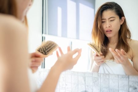 foto de mulher na frente do espelho olhando para uma escova de cabelo