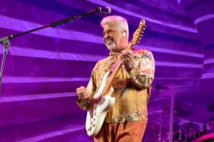 Foto colorida de Lulu Santos com uma guitarra na mão durante show - Metrópoles