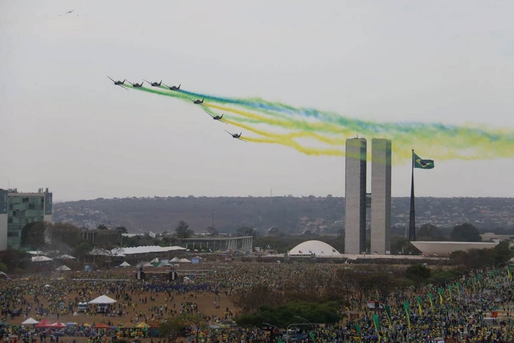 imagem colorida mostra aviões da esquadrilha da fumaça passando em frente ao congresso nacional com fumaças nas cores verde e amarelo - Metrópoles