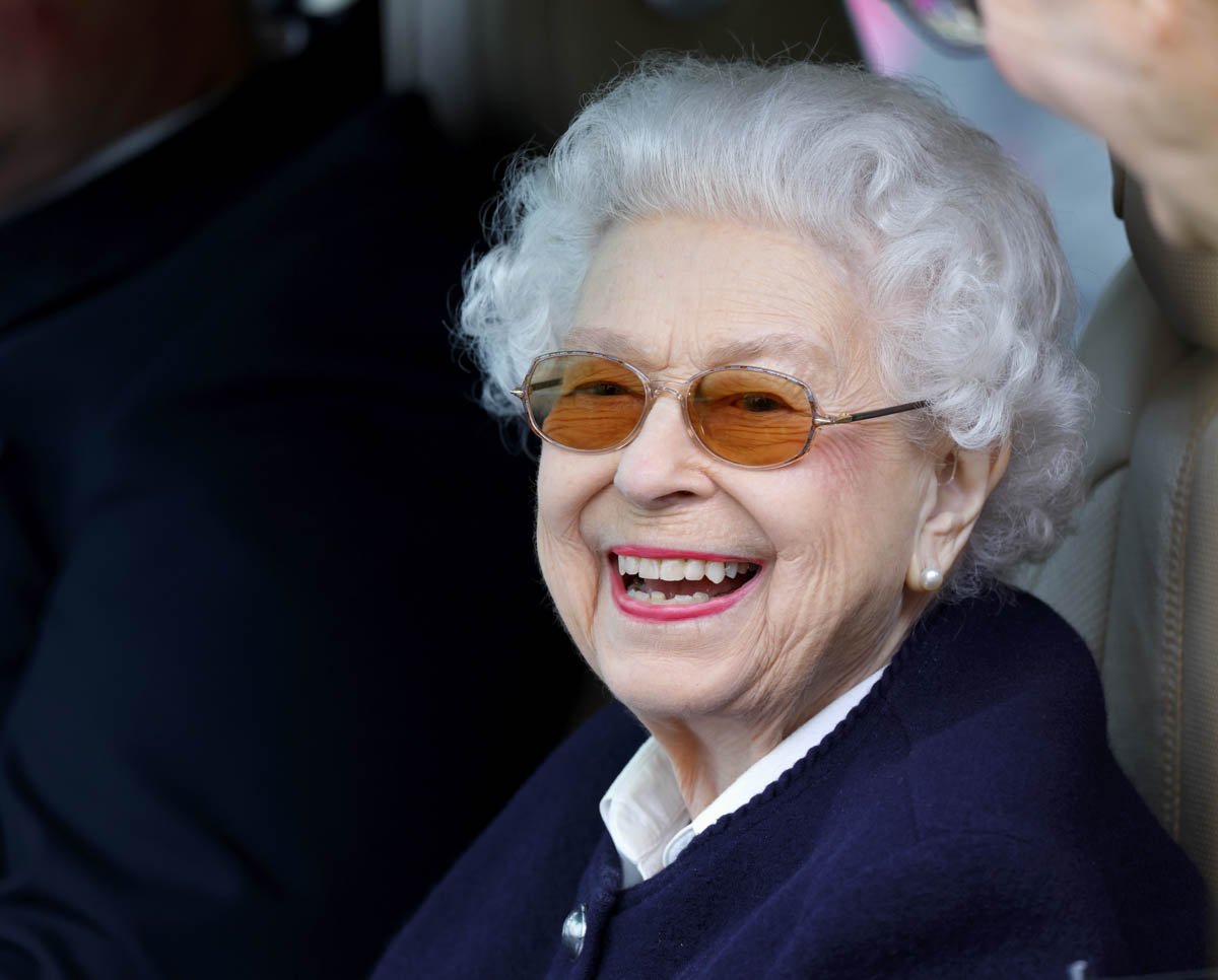 A rainha Elizabeth II com óculos escuros sorri para a fotografia