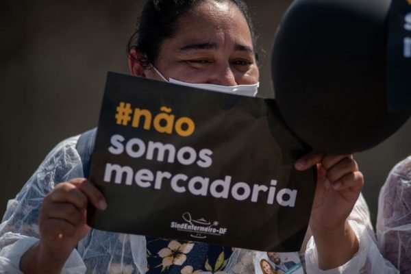 Mulher com placa preta escrita "não somos mercdoria"