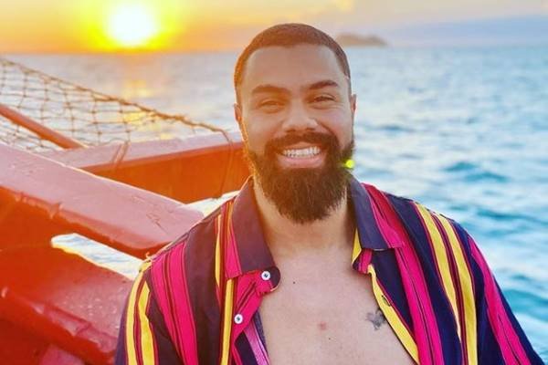 Fotografia colorida de homem com camisa listrada na praia