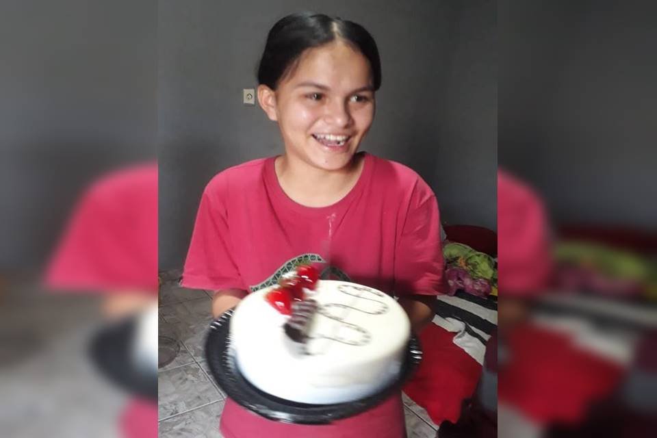 Menina com camisa rosa segurando bolo de aniversário