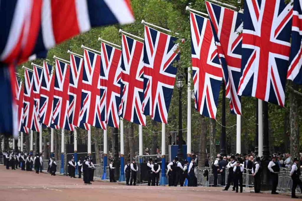 Bandeiras da União são vistas no The Mall enquanto os policiais metropolitanos se reúnem à frente da procissão para o Estado Deitado da Rainha Elizabeth II