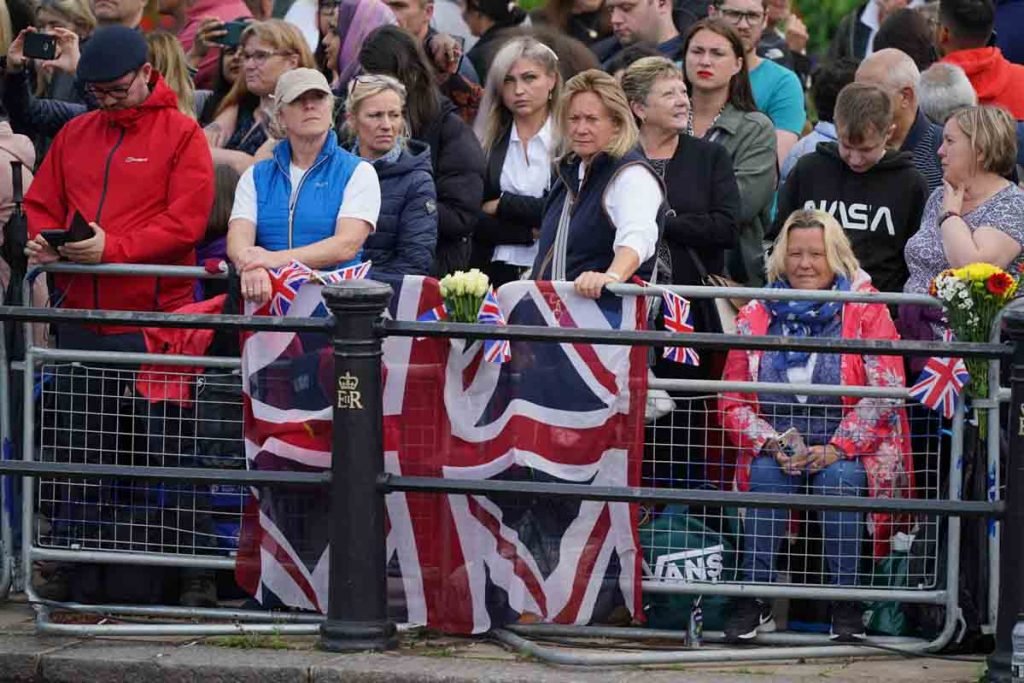 Membros do público aguardam perto do Palácio de Buckingham antes da procissão
