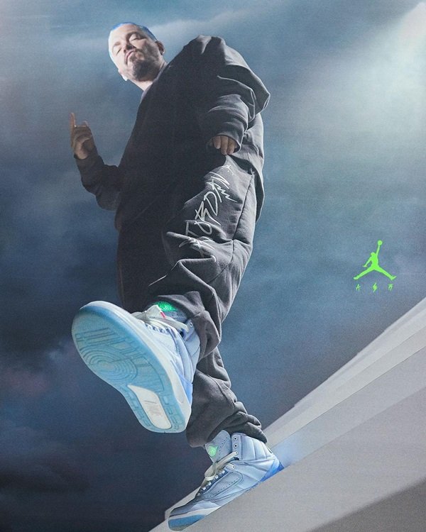 Campanha de divulgação da parceria entre a marca Jordan, do jogador de basquete Michael Jordan, com o cantor J Balvin. Os itens são feitos pela Nike. Na foto, é possível ver J Balvin com um moletom e uma calça, ambos pretos, e o tênis da coleção que é lilás com detalhes em azul claro e branco.