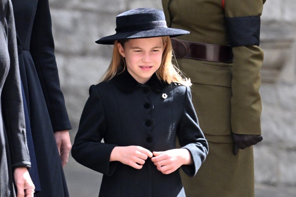 Foto colorida de menina usando vestido preto e chapéus preto. Princesa Charlotte-Metrópoles
