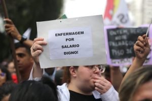 imagem colorida mostra pessoa segurando cartaz escrito "enfermagem por um salário digno" - Metrópoles