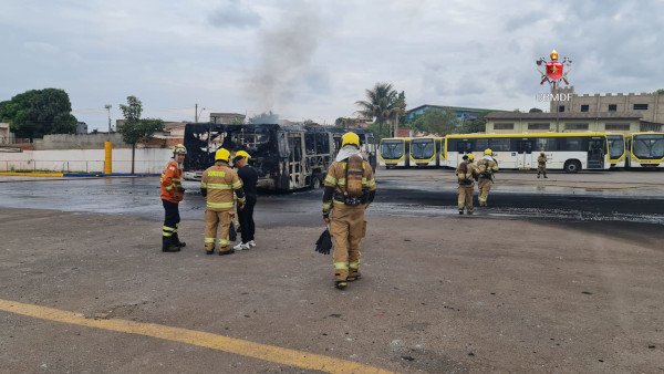 bombeiros em frente a carcaça de ônibus
