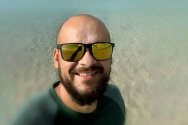Fotografia colorida de homem com óculos de sol em praia