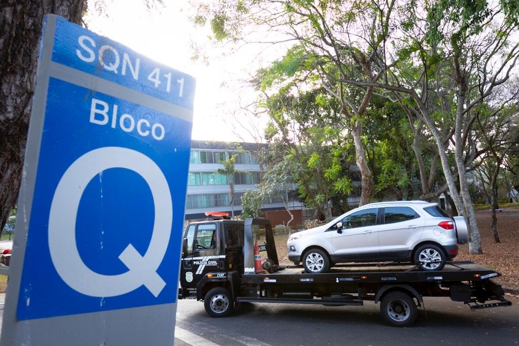 O guincho da perícia retirando o carro da vítima do estacionamento do bloco
