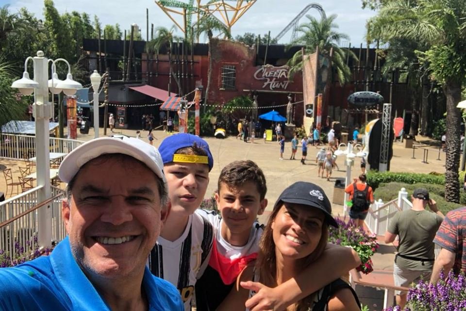 Família sorrindo para selfie em parque de diversão