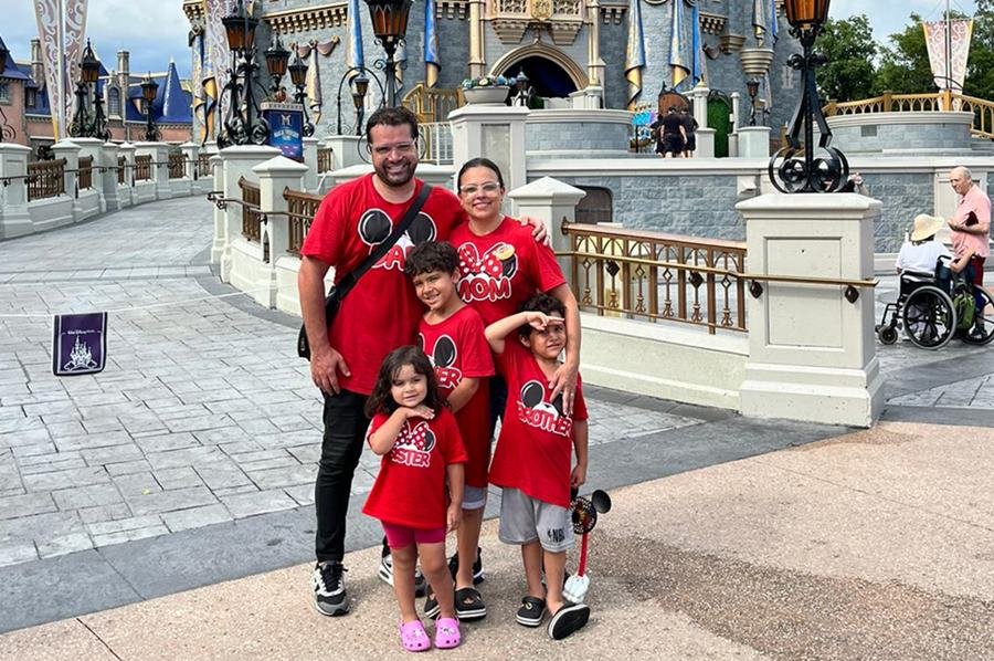 Família de vermelho em frente a castelo na Disney