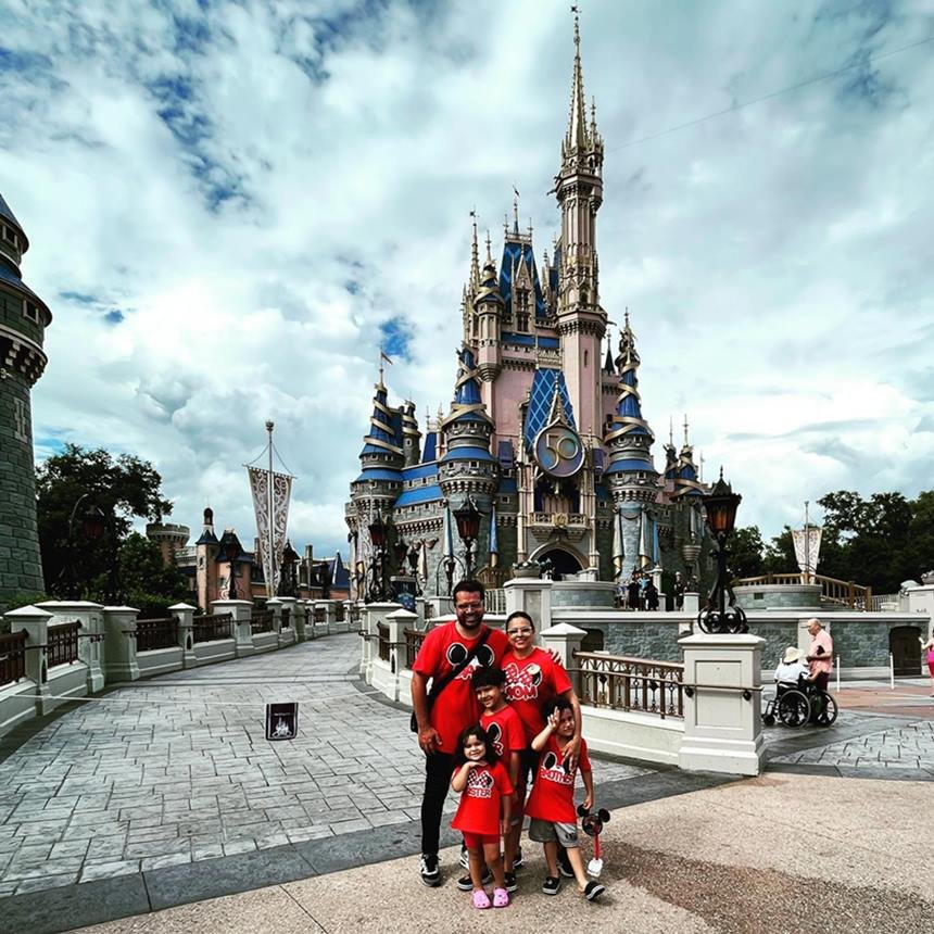 Família de vermelho em frente a castelo na Disney