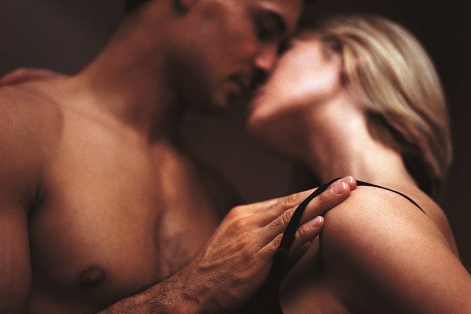 Foto desfocada de casal se beijando com o homem tirando a alça do sutiã da mulher - Metrópoles