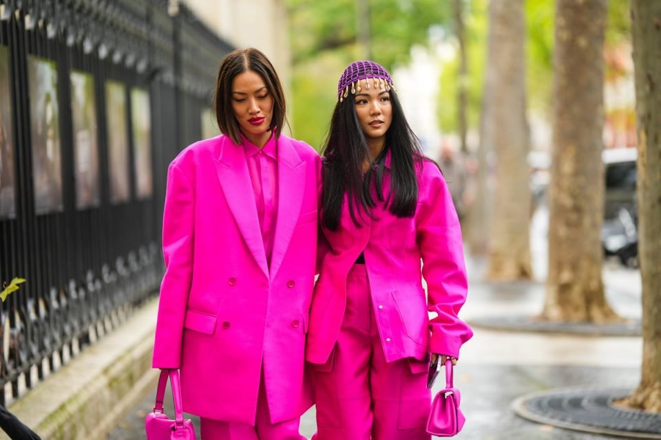 Looks em rosa, da estética barbiecore, no street style. Na imagem, duas mulheres usam peças de alfaiataria no tom vibrante