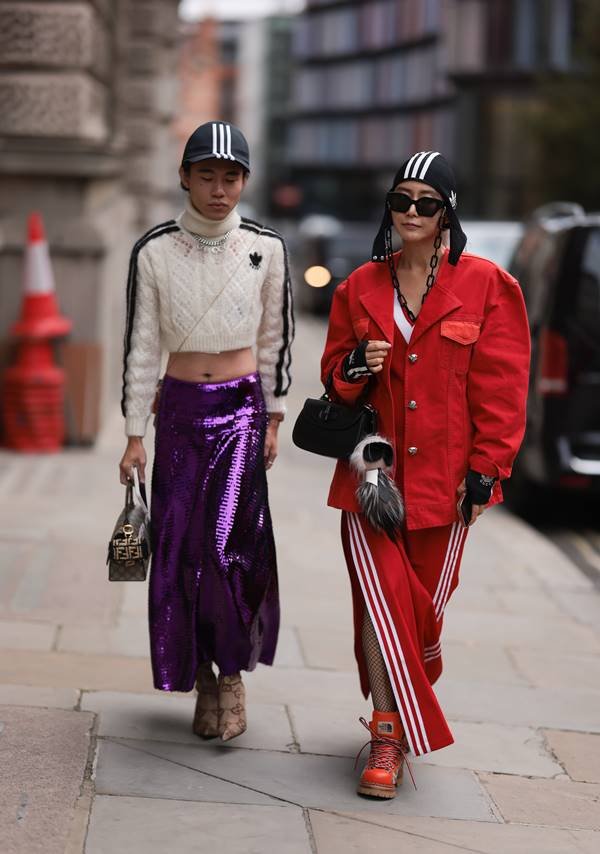 Looks de street style com peças esportivas. De um lado, saia roxa brilhosa. Do outro, visual vermelho com jaqueta