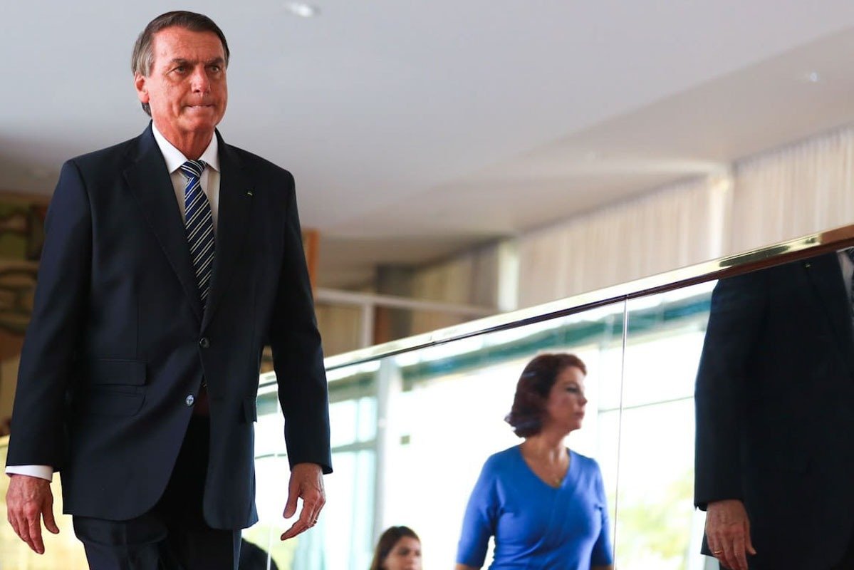 Presidente Bolsonaro anda pelo salão principal do Palácio do Planalto após reunião com prefeitos. Em segundo plano, a deputada Carla Zambelli - Metrópoles