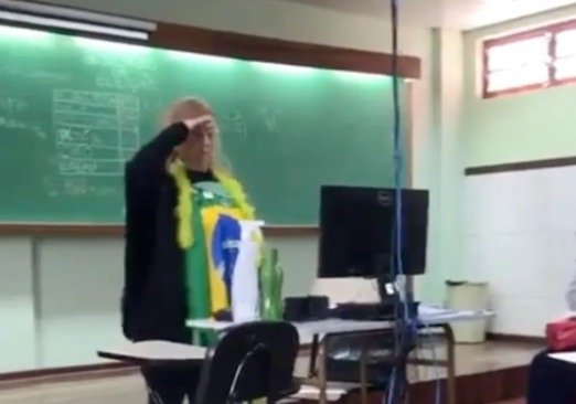 foto colorida de mulher em escola com bandeira do brasil fazendo gesto nazista
