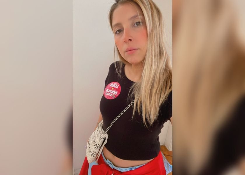 foto colorida de mulher loira de blusa preta com adesivo do Lula